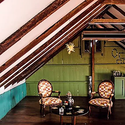 Interior de Casa Cino Fabiani: vigas de madera, paredes verdes y sillones antiguos