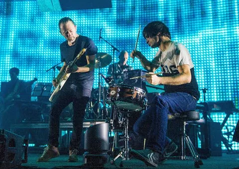 Radiohead tocando en vivo frente a una pantalla azul