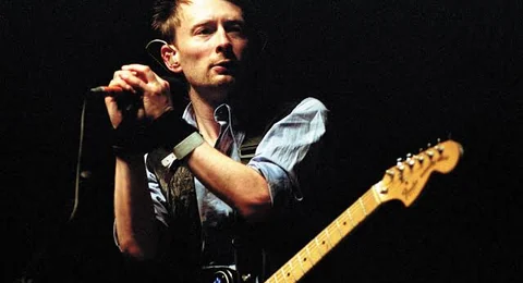 Thom Yorke cantando al micrófono con su guitarra